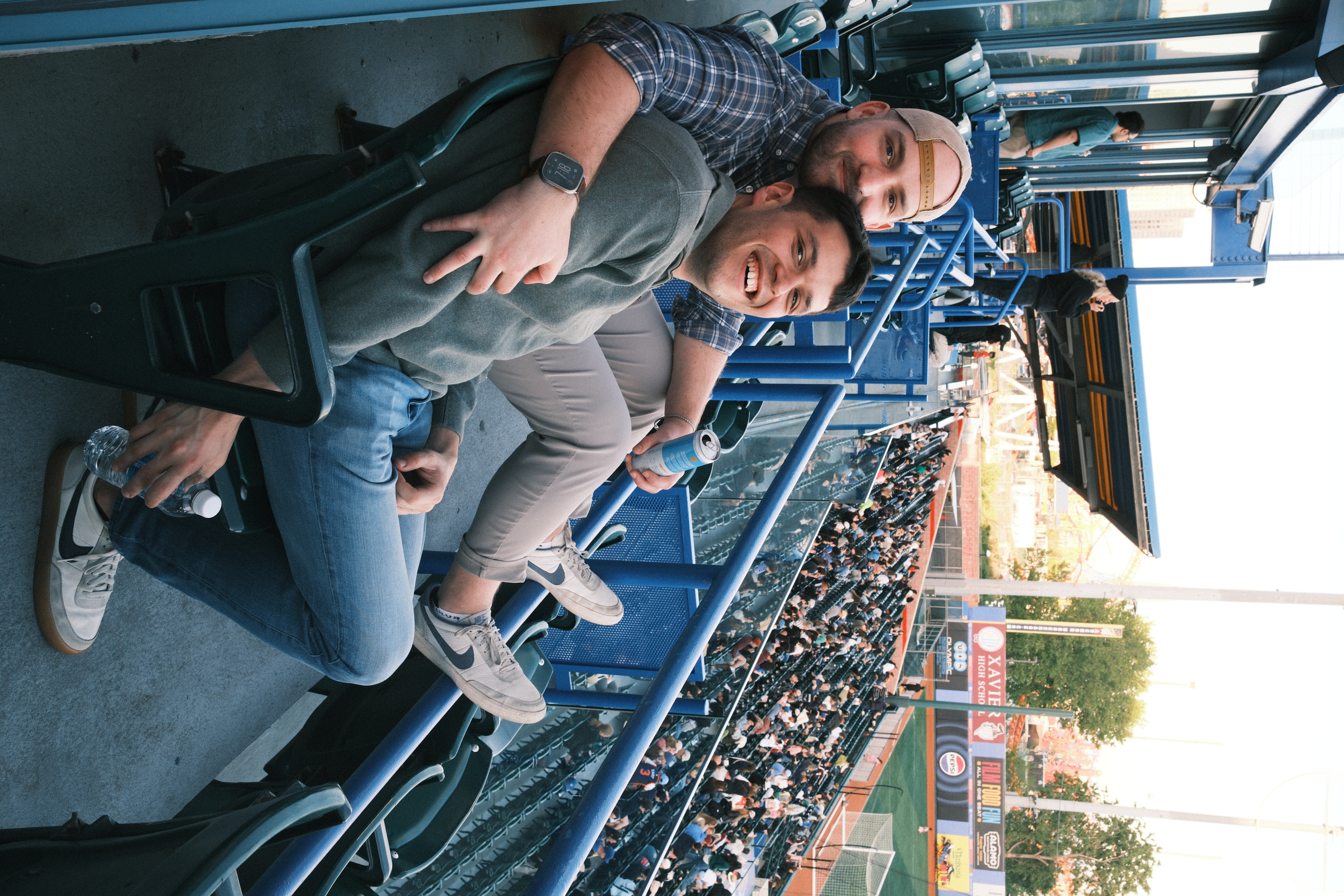 Ian and Zach laughing and relaxing in the stands at a baseball game